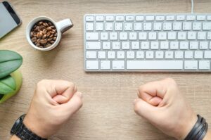 person near apple keyboard and cup with coffee beans