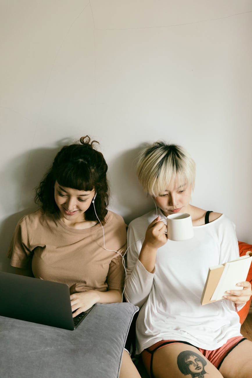 women using laptop and reading book together